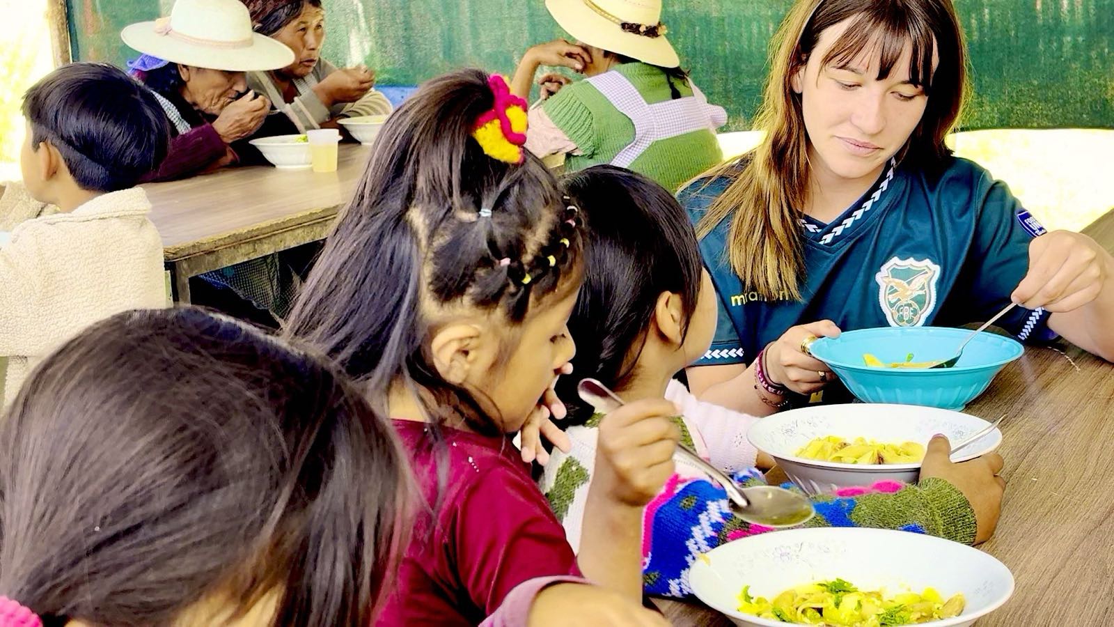 A volunteer shares a meal with children at the comedor in Cochabamba