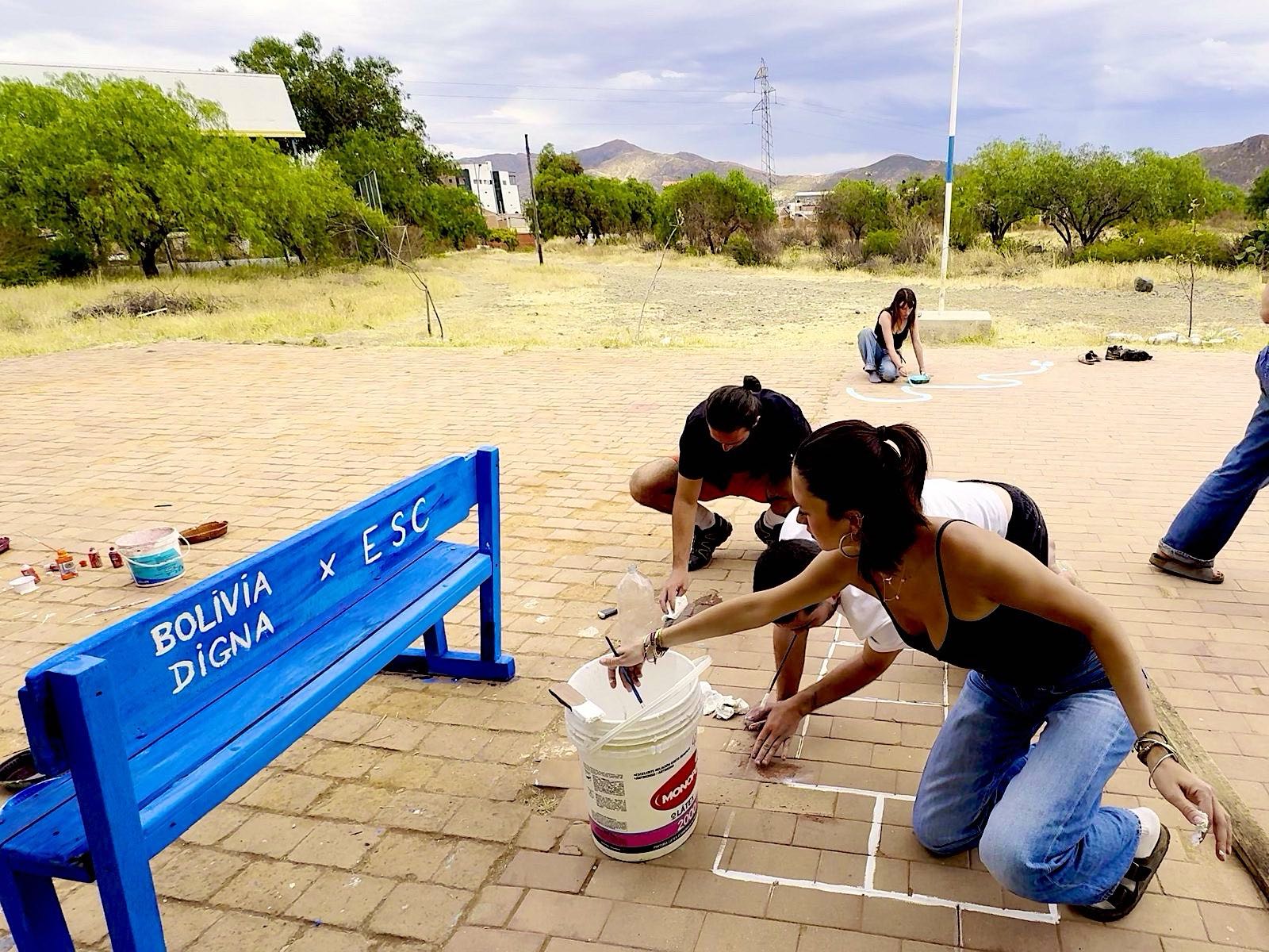 Volunteers painting the blue Bolivia Digna y E.S.C. bench