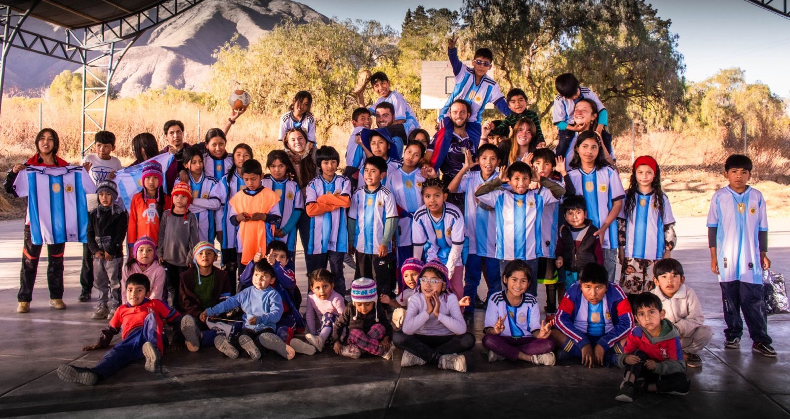 Children from the centre in football shirts with the volunteers, in Bolivia