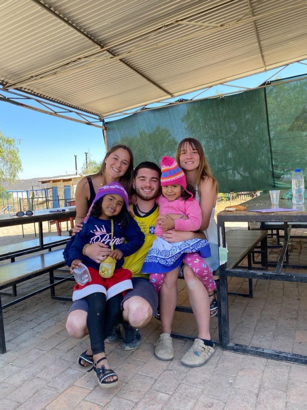 Three volunteers with two little girls under the centre's shelter