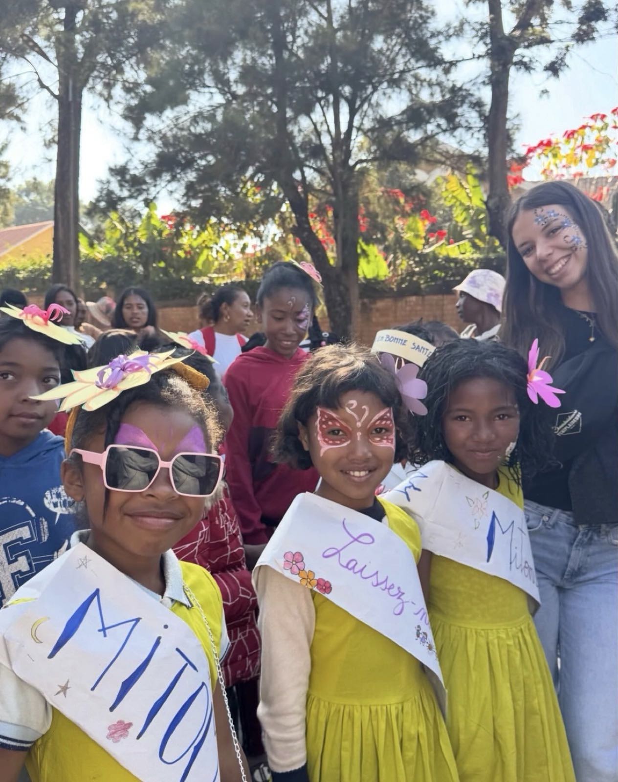 Children in yellow dresses and a smiling volunteer, faces painted, at a celebration in Madagascar