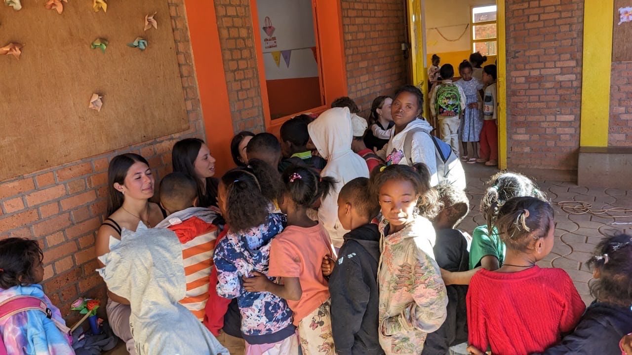 Volunteers surrounded by children in the centre's courtyard, in Madagascar
